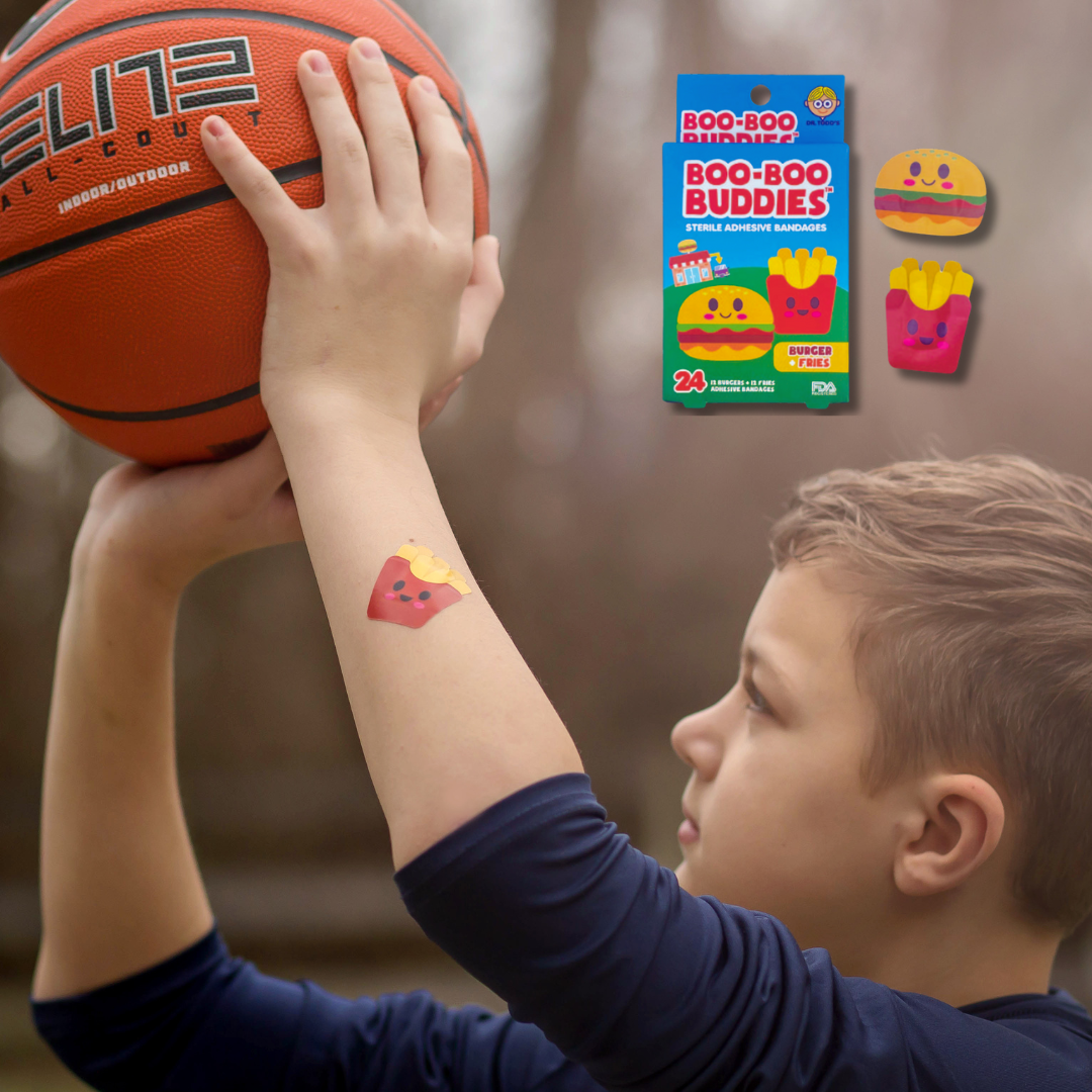 Child playing basketball while wearing Boo Boo Buddies fun and colorful kids bandages on his arm.