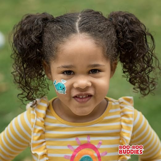 Happy girl wearing Boo-Boo Buddies® Narwhal shape bandage – colorful waterproof bandage for kids, perfect for cheeks, daycare, or outdoor fun