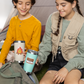 Two children sitting outdoors with camping gear and thermos cups with boo boo buddies stickers.